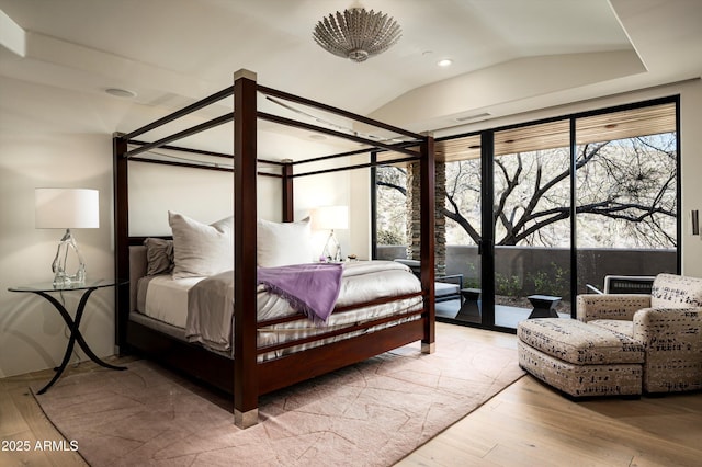 bedroom with access to exterior, visible vents, vaulted ceiling, and wood finished floors