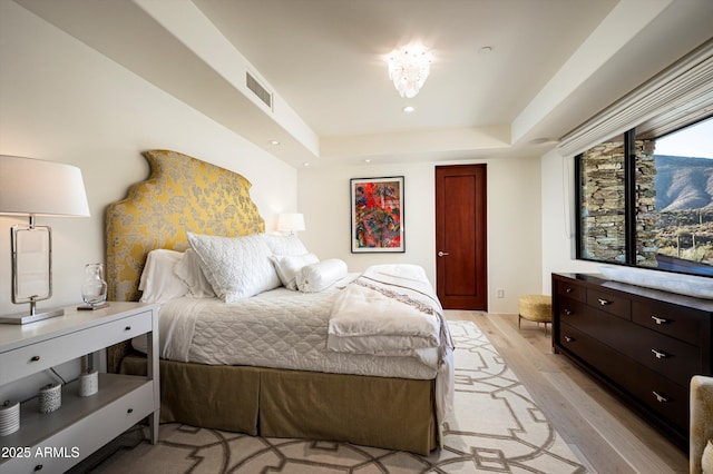 bedroom with recessed lighting, a raised ceiling, visible vents, and light wood-style flooring