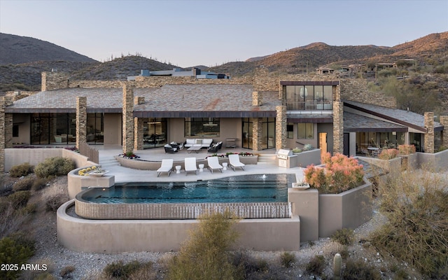 back of property featuring a patio area, a mountain view, and an outdoor pool