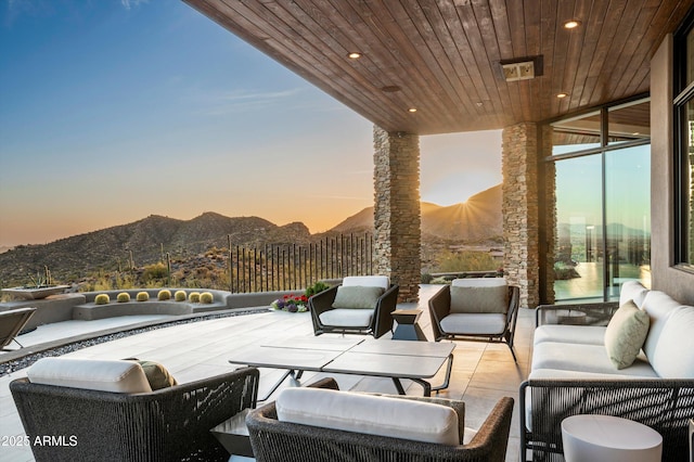 patio terrace at dusk with an outdoor hangout area and a mountain view