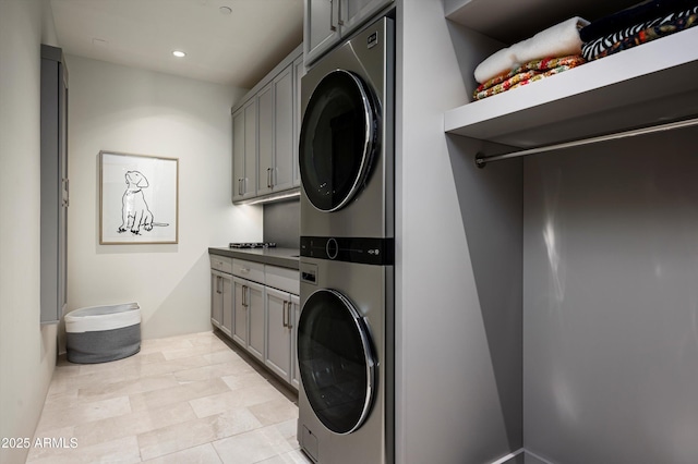 laundry area featuring stacked washer / dryer, cabinet space, and recessed lighting