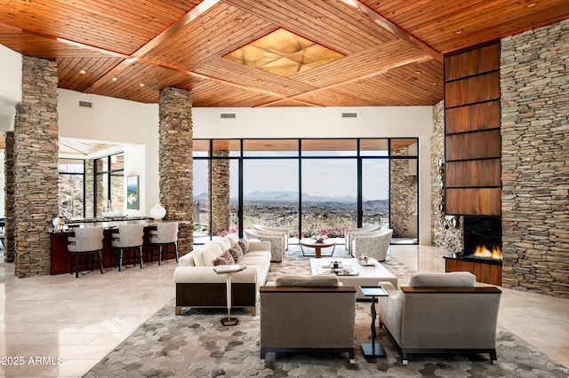 unfurnished living room with decorative columns, wooden ceiling, visible vents, a mountain view, and a warm lit fireplace