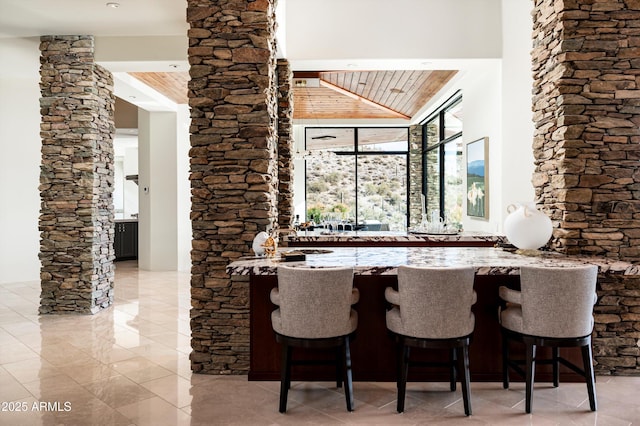 bar with wood ceiling, high vaulted ceiling, and indoor wet bar