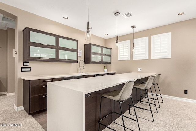 kitchen with decorative light fixtures, a breakfast bar, sink, and dark brown cabinets