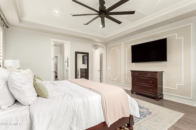 bedroom with ceiling fan, ornamental molding, a raised ceiling, and hardwood / wood-style floors