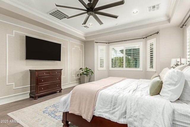 bedroom with ornamental molding, dark hardwood / wood-style floors, ceiling fan, and a tray ceiling