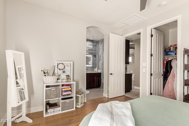 bedroom featuring connected bathroom and light hardwood / wood-style flooring