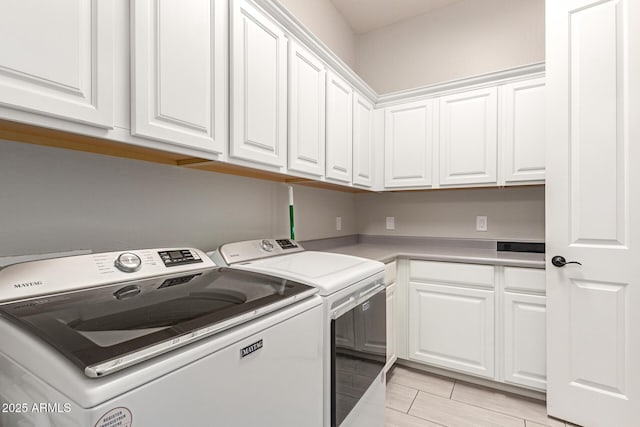 clothes washing area featuring cabinets and washer and dryer