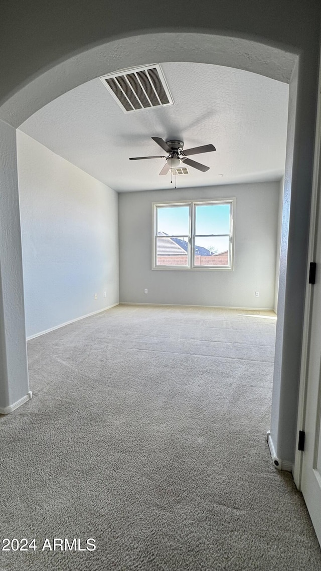 carpeted empty room with ceiling fan and a textured ceiling