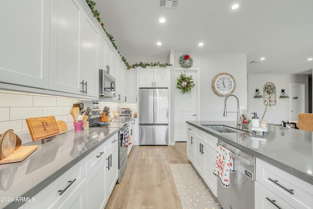 kitchen featuring sink, stainless steel appliances, dark stone countertops, decorative backsplash, and white cabinets