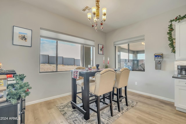 dining area featuring light wood-type flooring and a notable chandelier