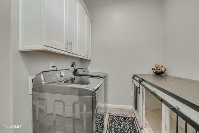 clothes washing area featuring cabinets and separate washer and dryer