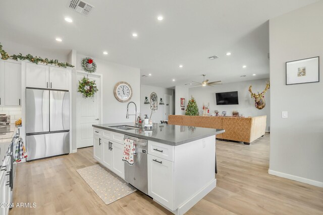 kitchen with white cabinets, sink, stainless steel appliances, and an island with sink