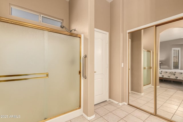 bathroom with a shower with door and tile patterned floors