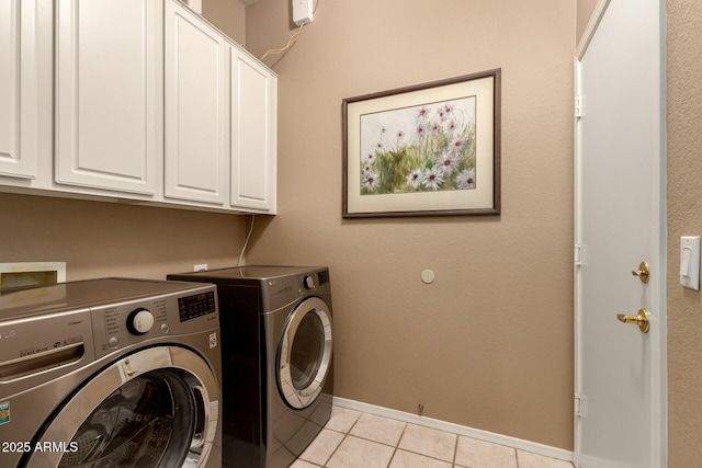 washroom featuring washing machine and clothes dryer, cabinets, and light tile patterned flooring