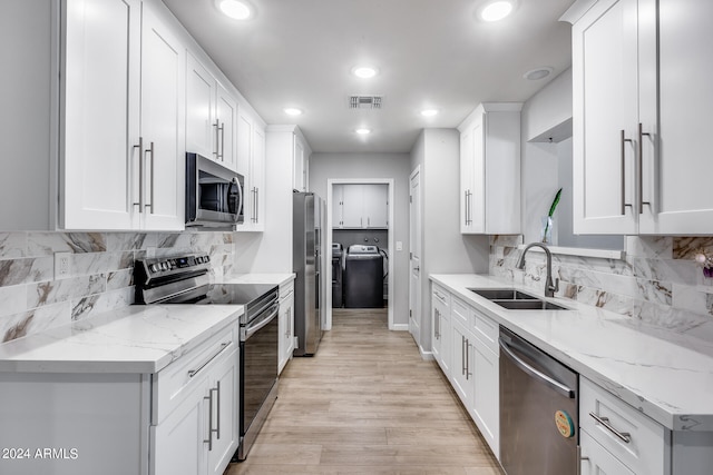 kitchen featuring appliances with stainless steel finishes, white cabinetry, light stone counters, and light hardwood / wood-style floors