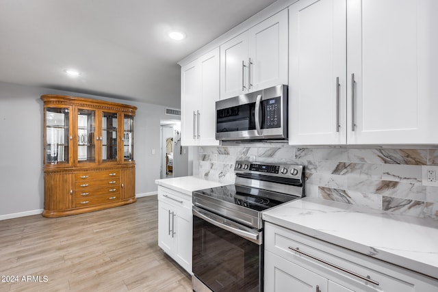 kitchen featuring light stone countertops, stainless steel appliances, white cabinets, and decorative backsplash