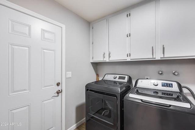 clothes washing area featuring washer and clothes dryer and cabinets