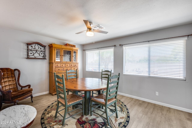 dining room with light wood-type flooring, a textured ceiling, and ceiling fan