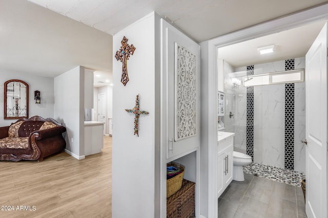 bathroom featuring vanity, toilet, wood-type flooring, and tiled shower