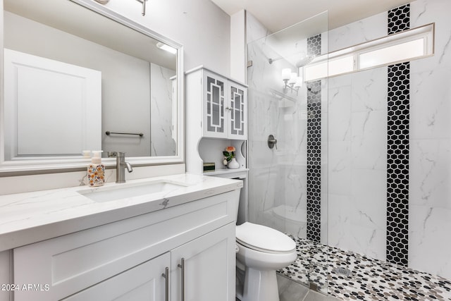 bathroom featuring tiled shower, toilet, and vanity