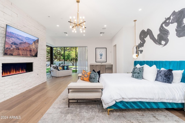 bedroom with wood-type flooring, a fireplace, and a chandelier