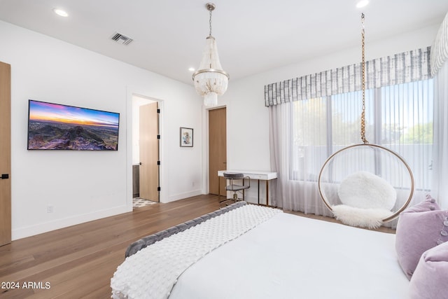 bedroom with wood-type flooring and an inviting chandelier