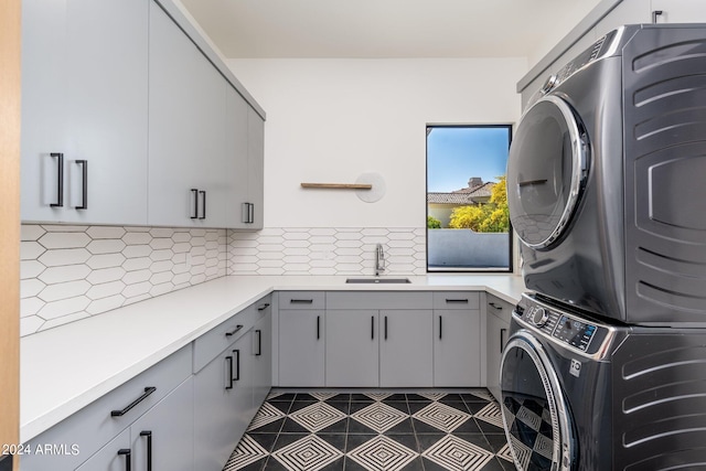 laundry room with stacked washer and clothes dryer, cabinets, and sink