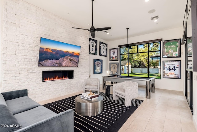 tiled living room featuring ceiling fan and a stone fireplace