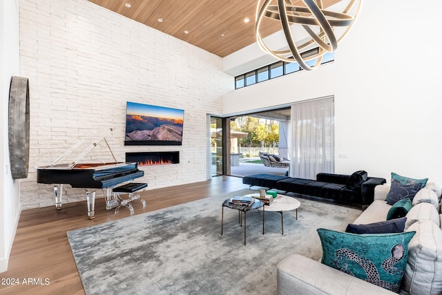 living room featuring a high ceiling, wooden ceiling, hardwood / wood-style floors, a notable chandelier, and a stone fireplace