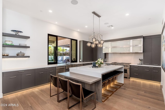 kitchen featuring stainless steel range, light hardwood / wood-style flooring, a center island, and a kitchen breakfast bar