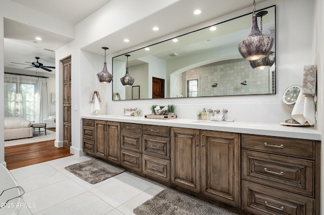 ensuite bathroom featuring a ceiling fan, double vanity, a sink, tile patterned flooring, and ensuite bathroom