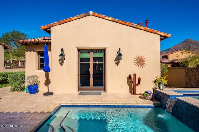 rear view of property featuring a patio area, stucco siding, french doors, and a tile roof