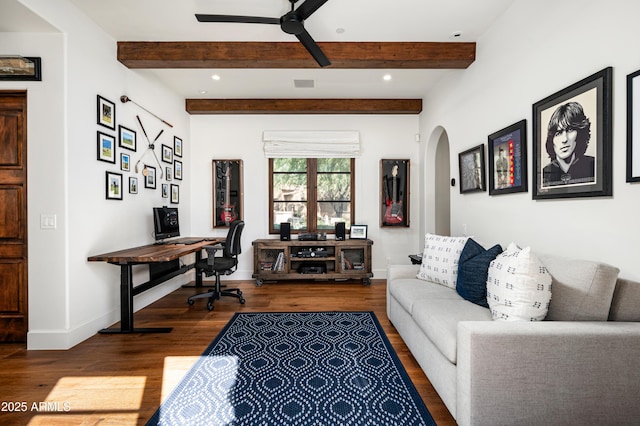 living area with baseboards, beamed ceiling, wood finished floors, arched walkways, and a ceiling fan