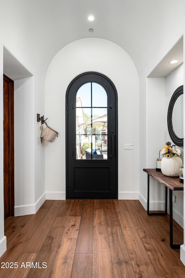 entryway featuring hardwood / wood-style flooring, baseboards, and vaulted ceiling