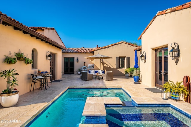 view of pool with an outdoor living space, a patio area, and a pool with connected hot tub