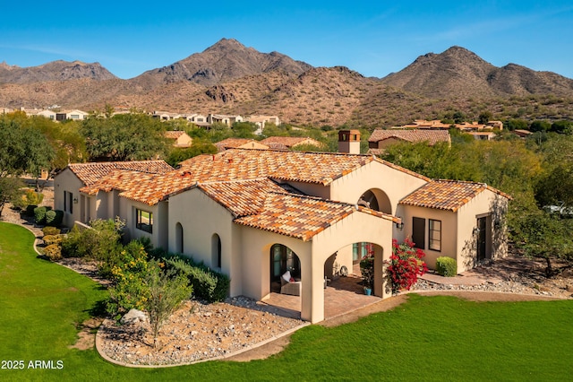 rear view of property featuring stucco siding, a patio area, a chimney, and a tile roof