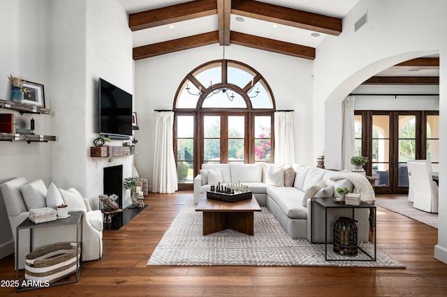 living area featuring visible vents, high vaulted ceiling, hardwood / wood-style flooring, french doors, and arched walkways