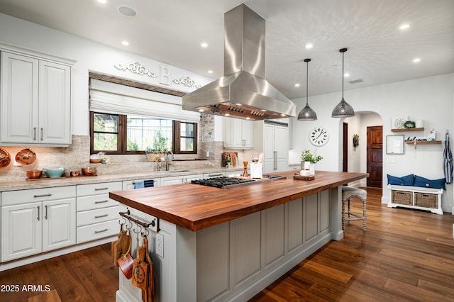 kitchen with island exhaust hood, stainless steel gas cooktop, butcher block countertops, and a sink