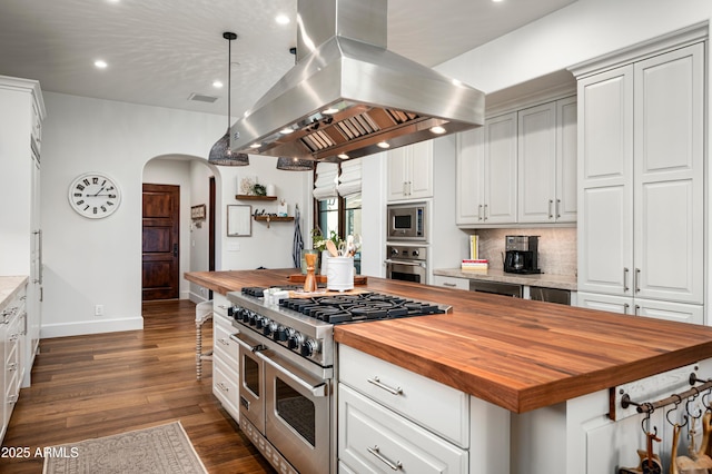 kitchen featuring dark wood finished floors, arched walkways, appliances with stainless steel finishes, butcher block counters, and island range hood