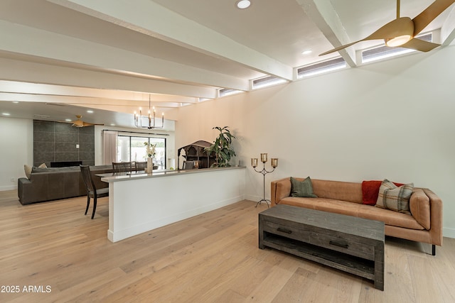 living room featuring a fireplace, beamed ceiling, light hardwood / wood-style floors, and a chandelier