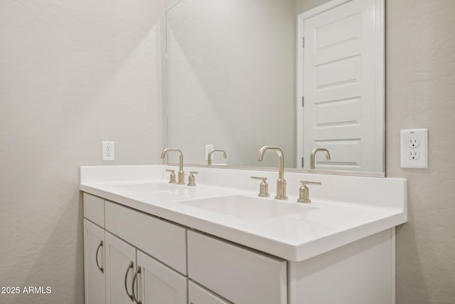 bathroom featuring double vanity, a textured wall, and a sink