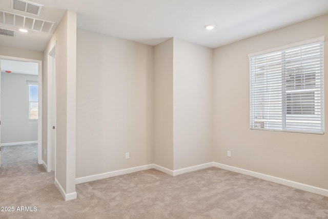 empty room with visible vents, baseboards, and light colored carpet