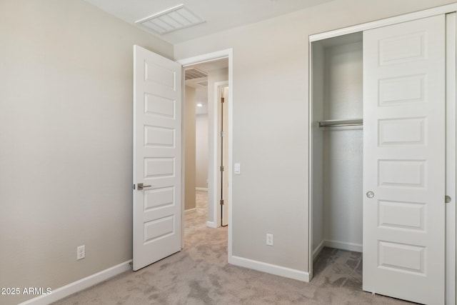 unfurnished bedroom featuring baseboards, a closet, light carpet, and visible vents