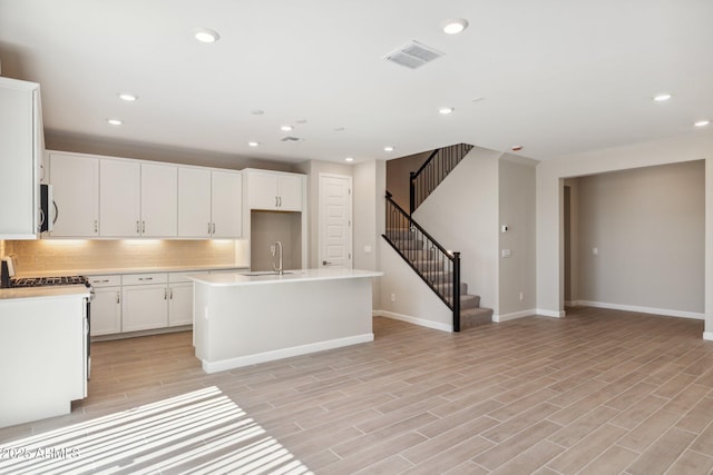 kitchen featuring tasteful backsplash, visible vents, wood tiled floor, light countertops, and a sink