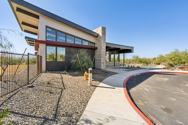 view of front of house with stucco siding, a patio, and fence