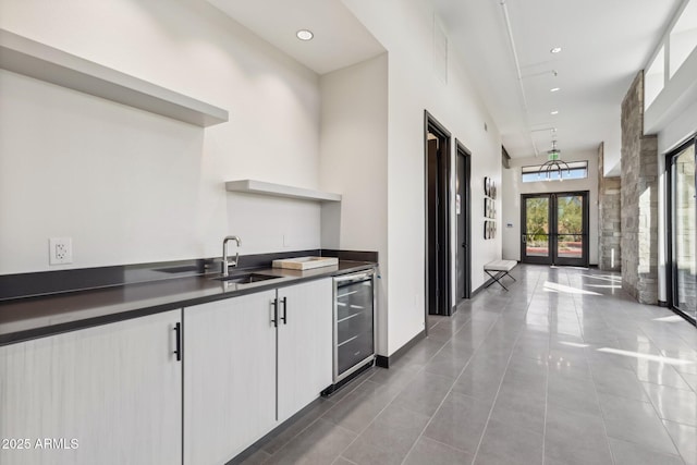 kitchen featuring dark countertops, a sink, wine cooler, french doors, and open shelves