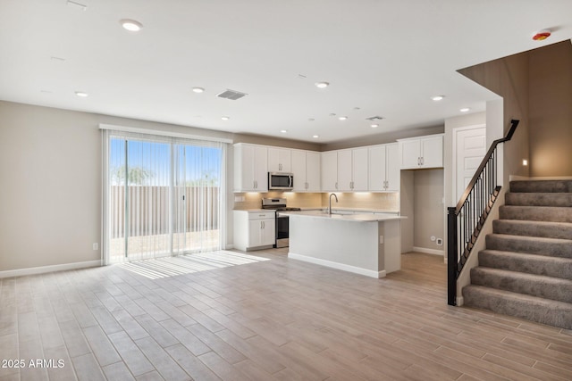 kitchen featuring visible vents, open floor plan, light countertops, stainless steel appliances, and a sink