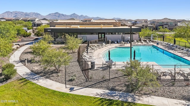 community pool with a mountain view, a patio area, and fence