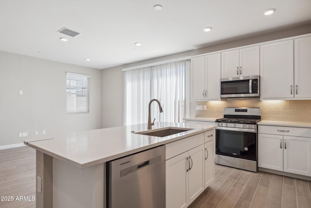 kitchen with a sink, stainless steel appliances, visible vents, and light wood-style flooring